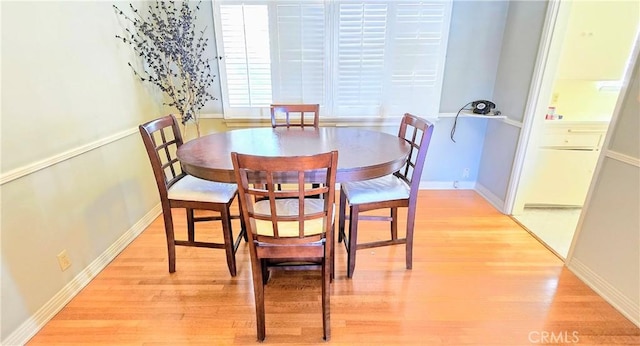 dining space with baseboards and light wood finished floors