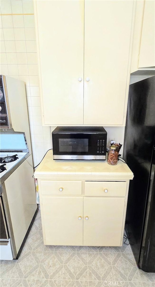 kitchen featuring freestanding refrigerator, light countertops, and range