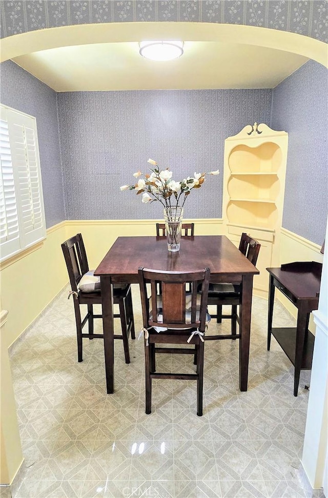 dining room featuring arched walkways and wallpapered walls