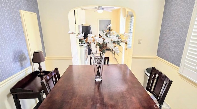 dining area with arched walkways, washer / clothes dryer, a ceiling fan, and wallpapered walls