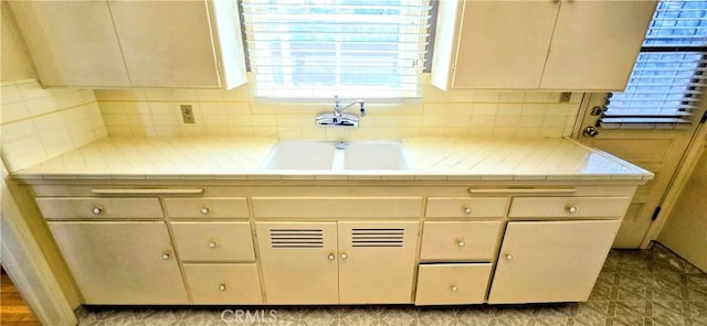 kitchen featuring tasteful backsplash, a sink, and tile countertops