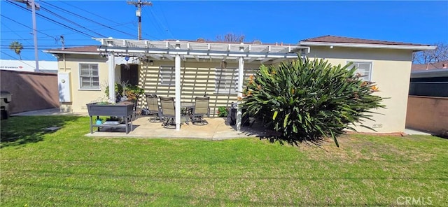 rear view of house with a yard, a pergola, and stucco siding