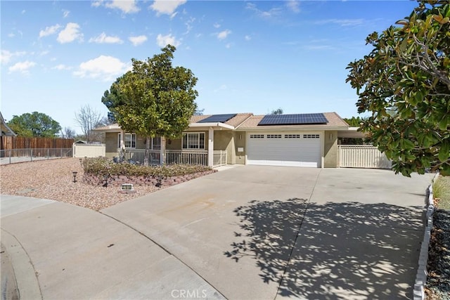 ranch-style home featuring a garage, concrete driveway, solar panels, fence, and stucco siding