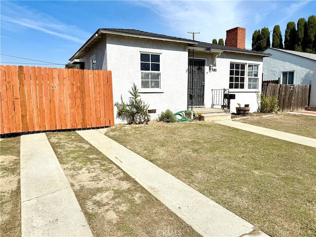 view of front of property with a chimney, stucco siding, crawl space, fence, and a front lawn