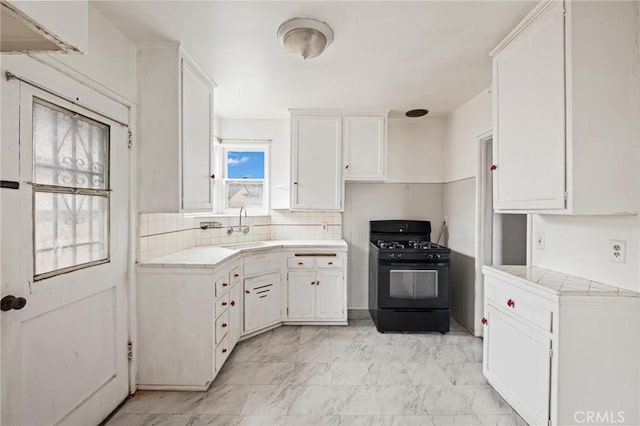 kitchen featuring a sink, black range with gas stovetop, white cabinets, and tile counters