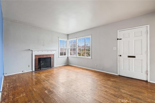 unfurnished living room with a fireplace, baseboards, and wood finished floors