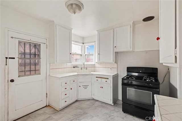 kitchen with black range with gas stovetop, a sink, and white cabinetry