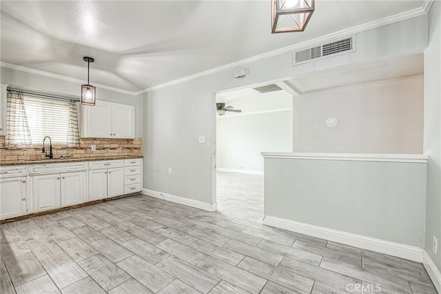 kitchen featuring decorative light fixtures, visible vents, a ceiling fan, white cabinets, and a sink