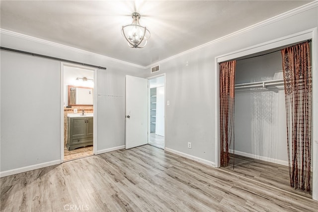 unfurnished bedroom featuring visible vents, baseboards, light wood-style floors, ornamental molding, and a closet