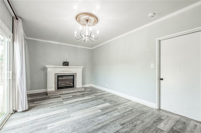 unfurnished living room with a notable chandelier, light wood-type flooring, a tile fireplace, and crown molding