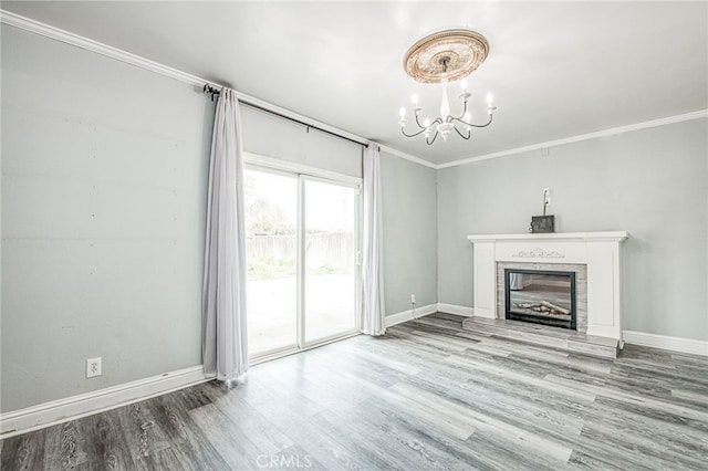 unfurnished living room featuring baseboards, a glass covered fireplace, ornamental molding, wood finished floors, and a chandelier