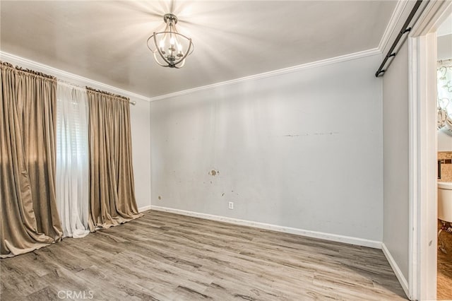 spare room with a notable chandelier, baseboards, crown molding, and wood finished floors