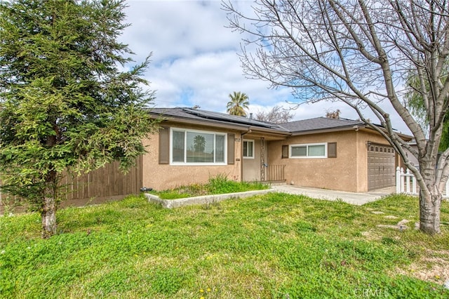 ranch-style house with a garage, solar panels, fence, stucco siding, and a front lawn