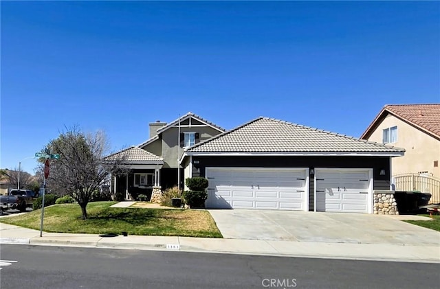 view of front of property with a garage, a front yard, concrete driveway, and a tiled roof