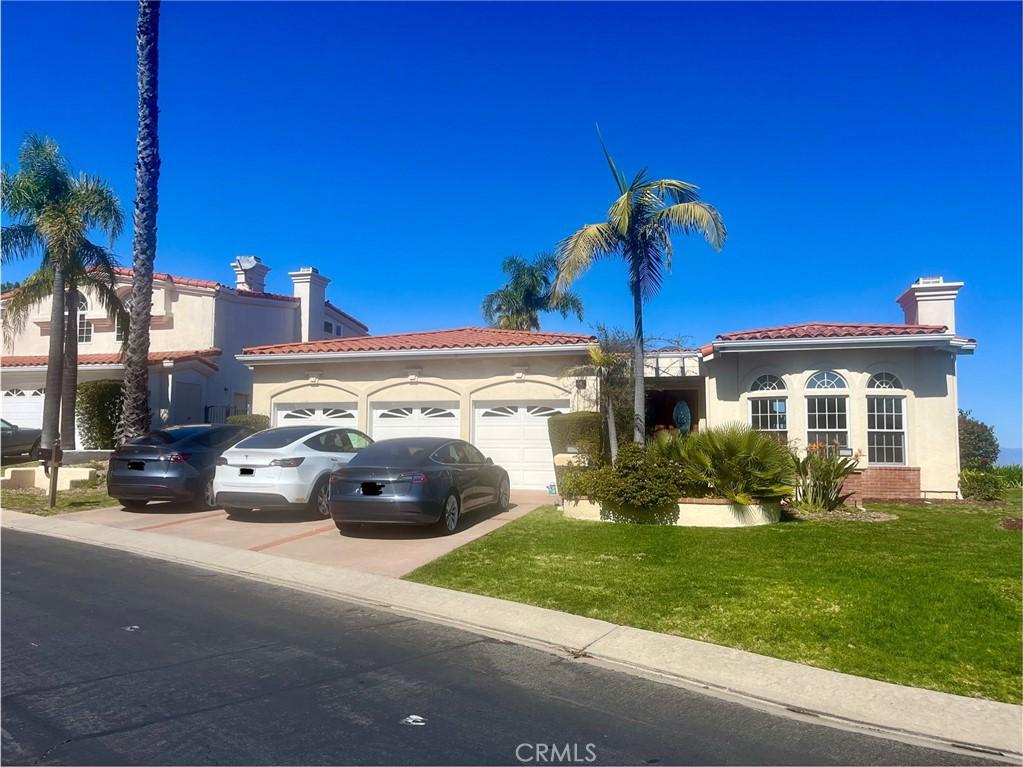 mediterranean / spanish home featuring a tile roof, a chimney, a garage, driveway, and a front lawn