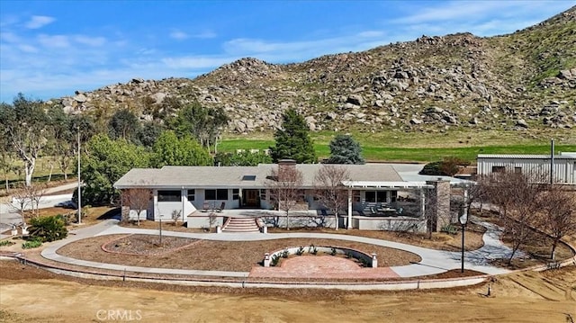 back of property with fence, a mountain view, and a patio