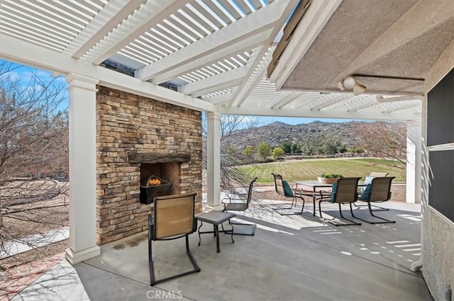 view of patio featuring an outdoor stone fireplace, a mountain view, and a pergola