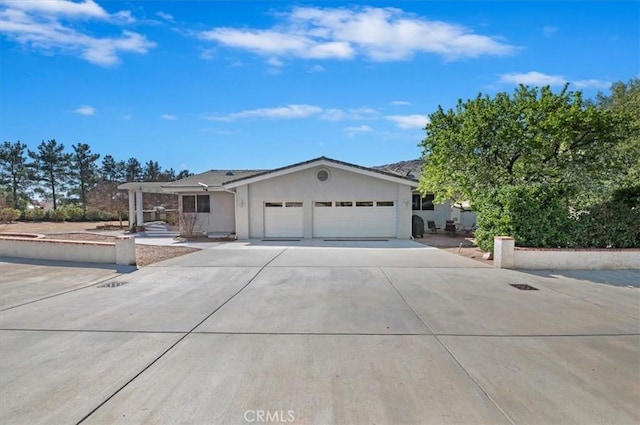 single story home featuring a garage, concrete driveway, and stucco siding