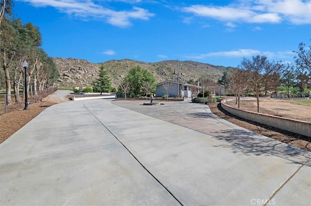 view of road featuring street lighting, concrete driveway, and a mountain view