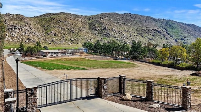 view of home's community featuring a gate, fence, a mountain view, and a lawn