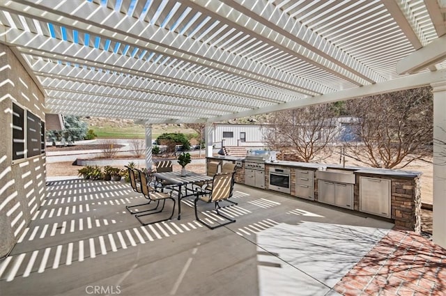 view of patio / terrace with outdoor dining area, area for grilling, a sink, exterior kitchen, and a pergola