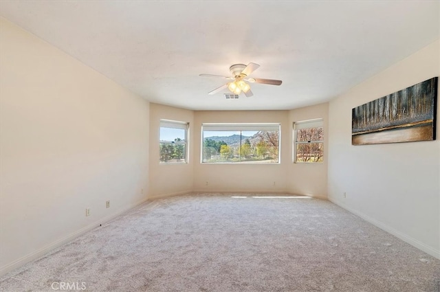 carpeted empty room with ceiling fan, visible vents, and baseboards