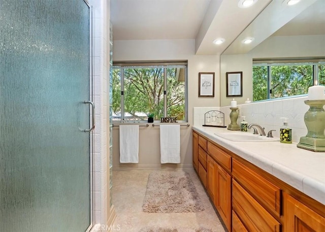 full bath with a shower stall, decorative backsplash, and vanity