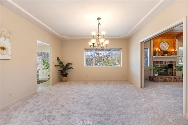 carpeted spare room featuring a glass covered fireplace and a notable chandelier