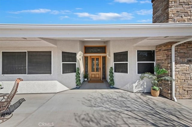 doorway to property featuring stone siding and stucco siding