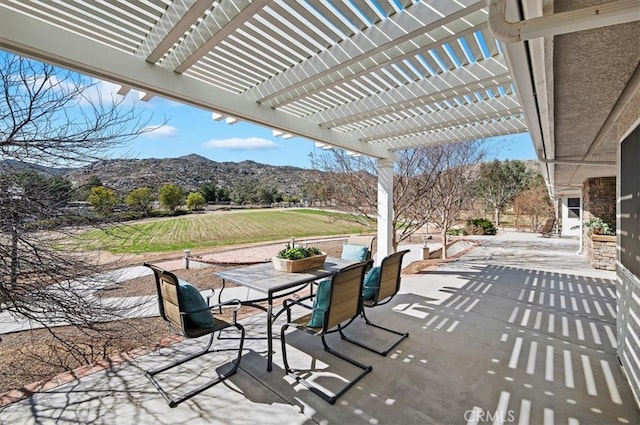 view of patio featuring outdoor dining area, a mountain view, and a pergola