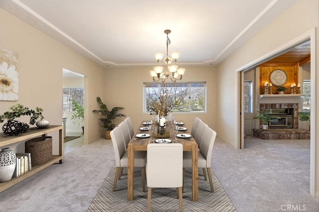 dining area with a fireplace, carpet flooring, and an inviting chandelier