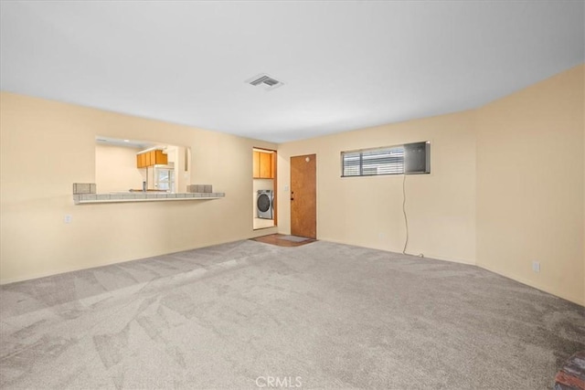 unfurnished living room with visible vents, carpet flooring, and independent washer and dryer