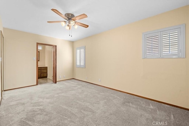 unfurnished bedroom with light carpet, ensuite bath, a ceiling fan, and baseboards