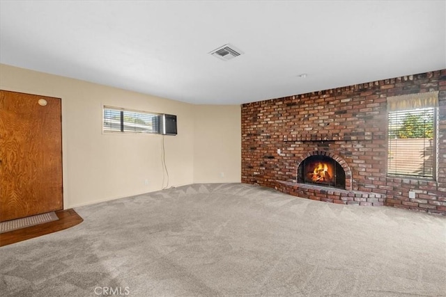 unfurnished living room with a fireplace, visible vents, and carpet flooring