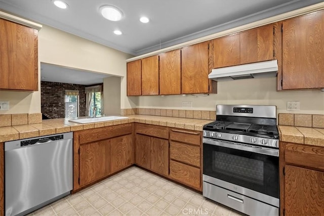 kitchen with stainless steel appliances, brown cabinetry, a sink, and under cabinet range hood