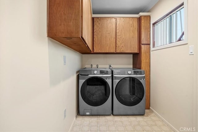 laundry area featuring washing machine and dryer, cabinet space, and baseboards