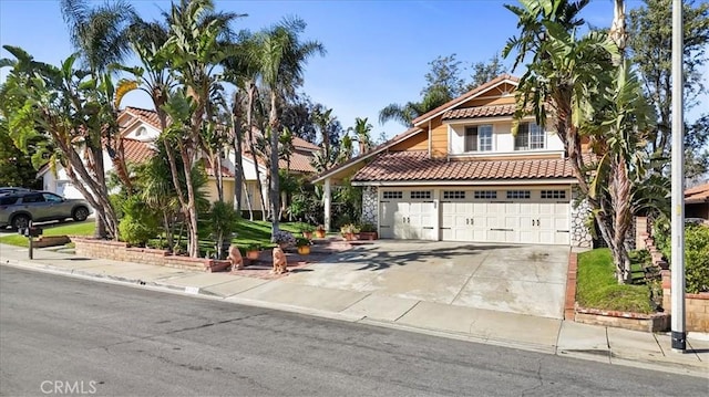 mediterranean / spanish-style house with a tiled roof, concrete driveway, and stone siding