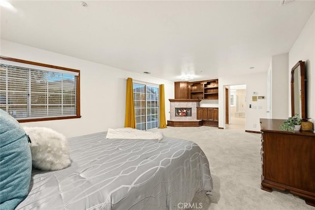 bedroom featuring a lit fireplace, carpet floors, and ensuite bathroom