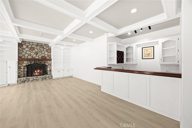 unfurnished living room with a fireplace, coffered ceiling, beam ceiling, and light wood-style floors