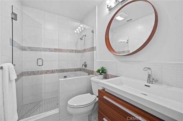 bathroom featuring visible vents, toilet, a tile shower, vanity, and tile walls