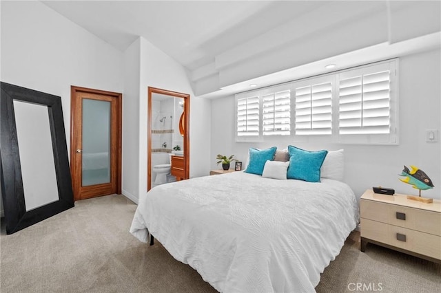 bedroom featuring lofted ceiling, baseboards, carpet, and ensuite bathroom