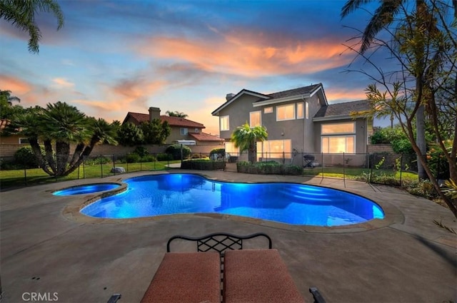 view of pool featuring a pool with connected hot tub, fence, and a patio