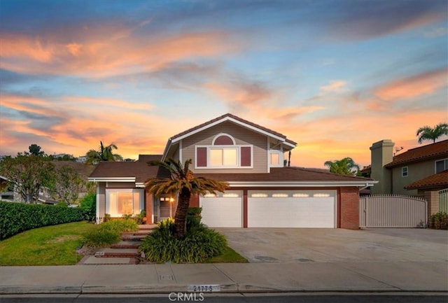 traditional-style home featuring driveway, fence, and a gate