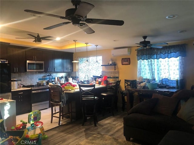 kitchen with decorative light fixtures, stainless steel appliances, light countertops, decorative backsplash, and a wall mounted AC