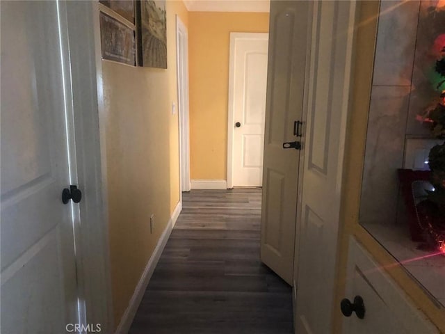 corridor featuring dark wood finished floors and baseboards