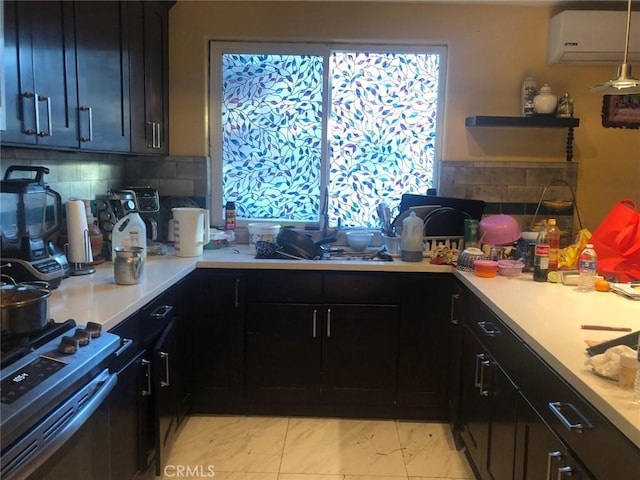 kitchen with pendant lighting, marble finish floor, light countertops, stove, and an AC wall unit