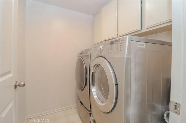 laundry room featuring washer and clothes dryer, cabinet space, and baseboards