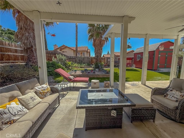 view of patio / terrace with outdoor lounge area, an outbuilding, a fenced backyard, and a shed