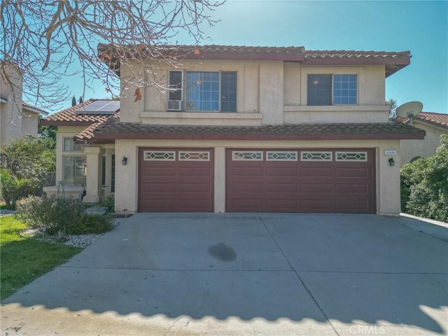 view of front of home with stucco siding, concrete driveway, a garage, a tile roof, and roof mounted solar panels