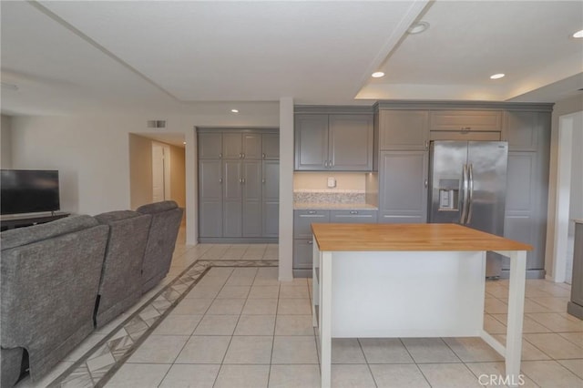 kitchen featuring wooden counters, stainless steel fridge with ice dispenser, open floor plan, gray cabinets, and a raised ceiling